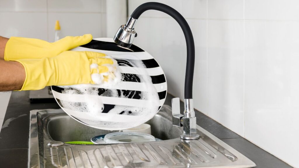 person washing a black and white sripped plate