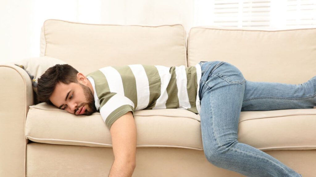 man laying on sofa procratinating