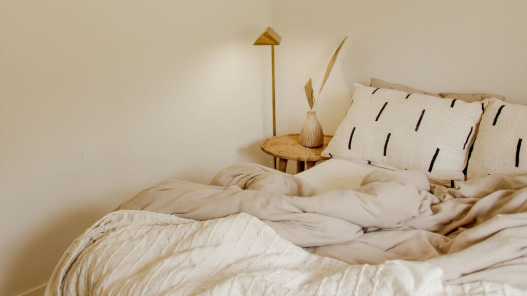 unmade bed with pillows, duvet and sheets