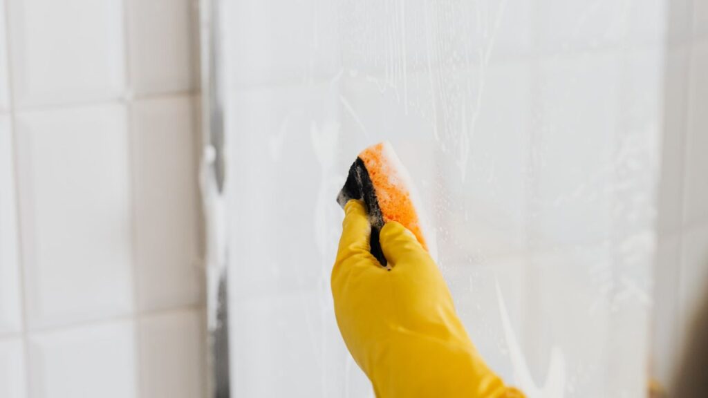 washing shower glass with a sponge