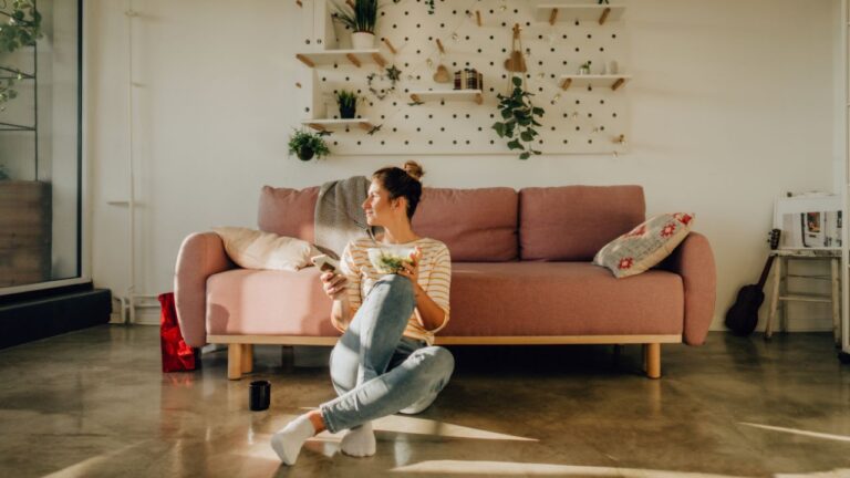 woman sitting in front couch eating salad