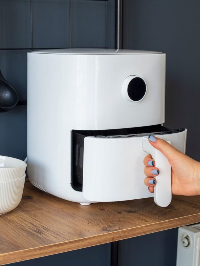 woman-opening-white-air-fryer-blue-kitchen-wall