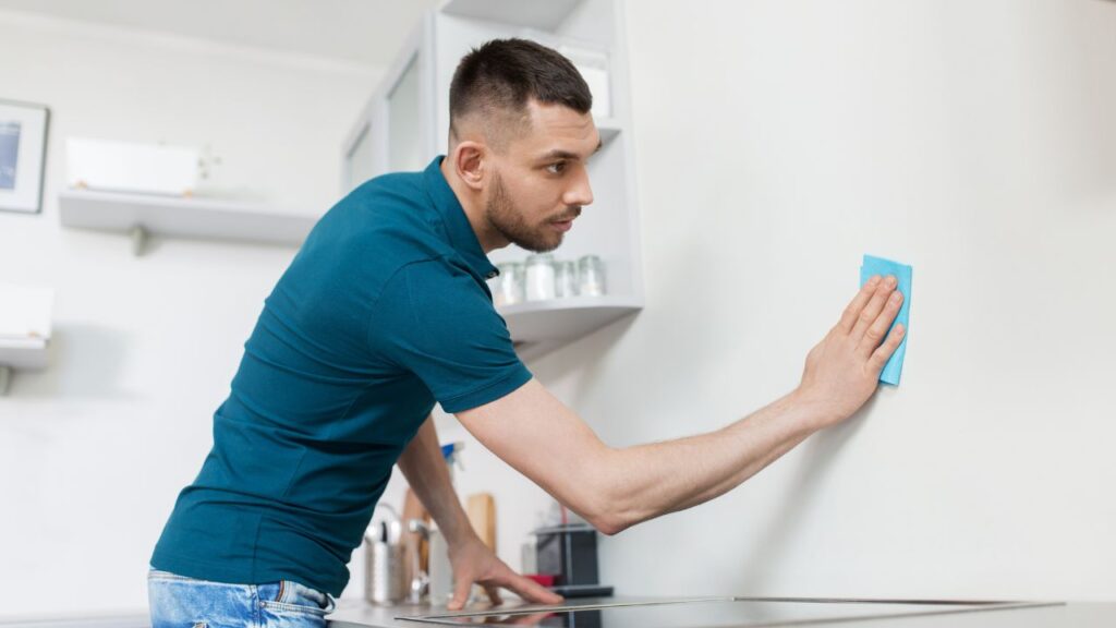 cleaning kitchen wall by wiping the surface