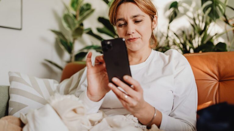 woman looking through phone sitting leather couch